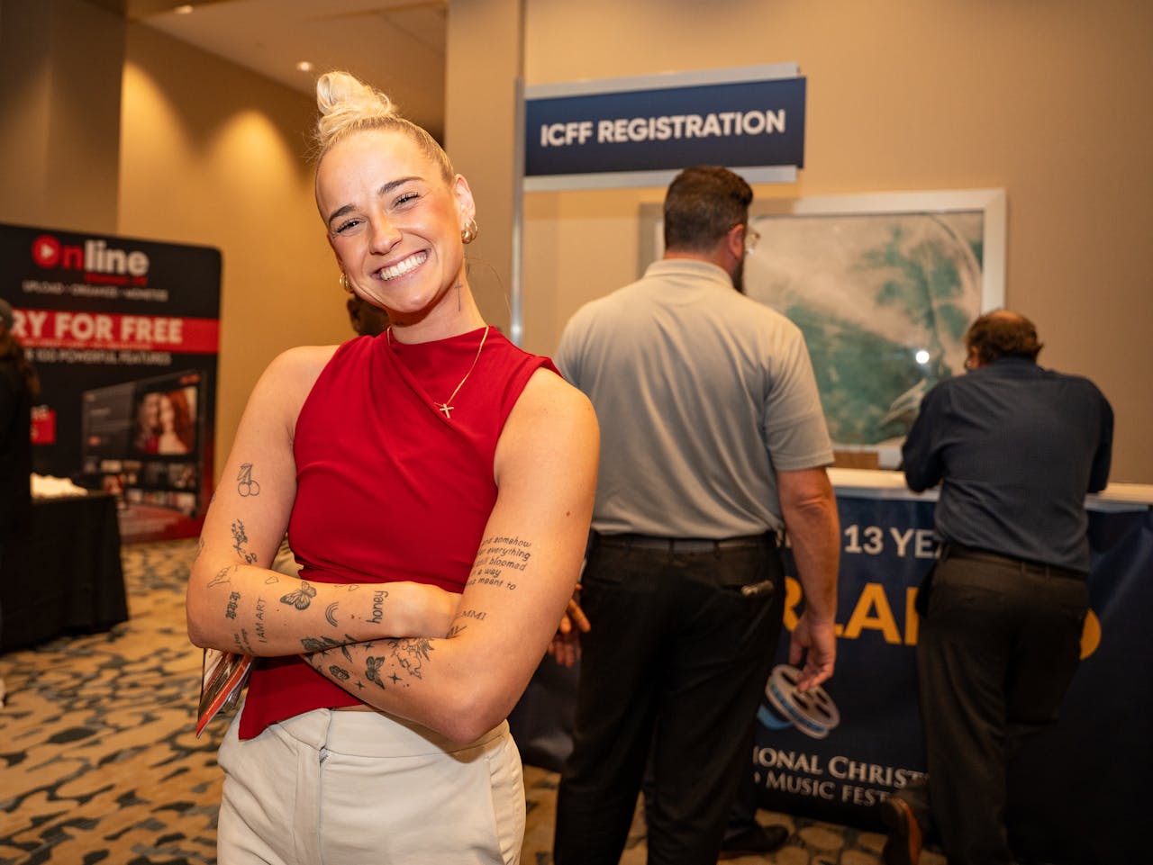 A cheerful woman in a red top stands confidently at the ICFF registration desk.